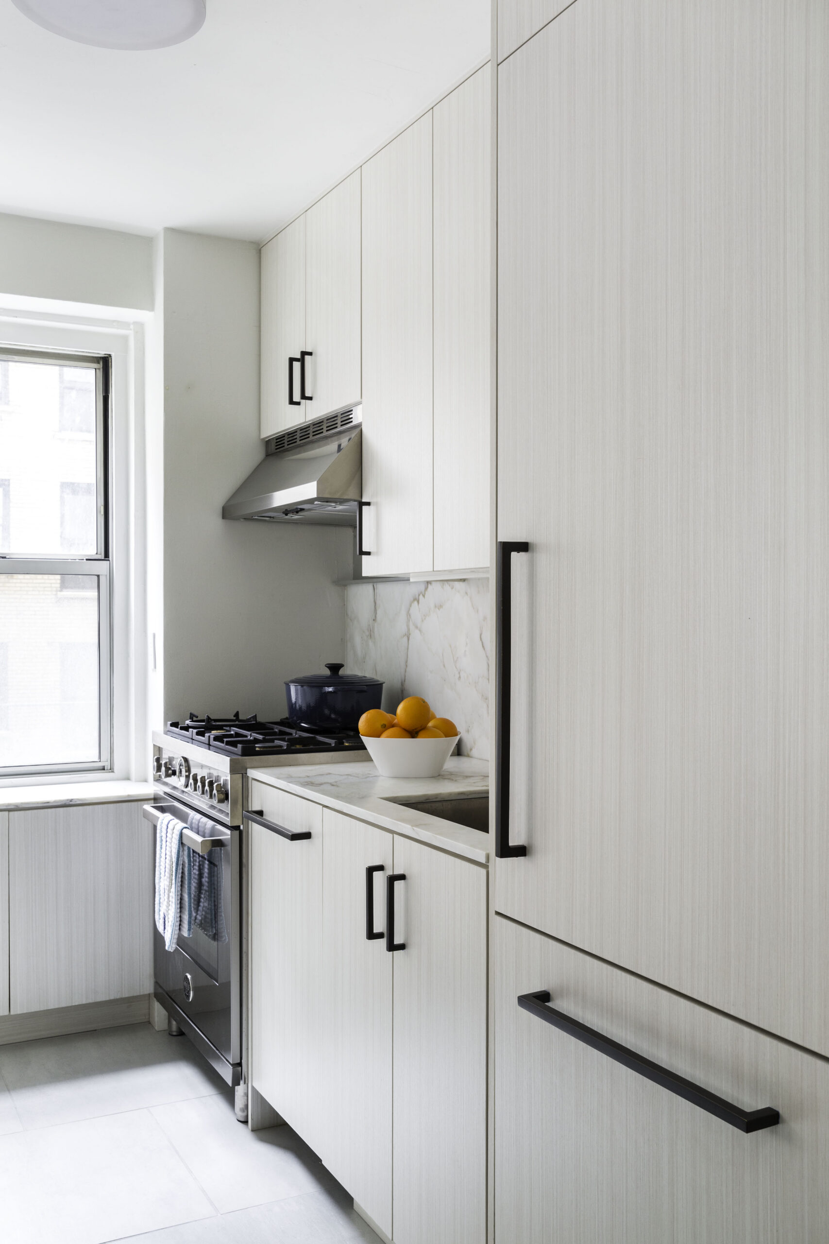 Kitchen with Calacatta marble backsplash, cabinets, drawers, and stainless steel range hood