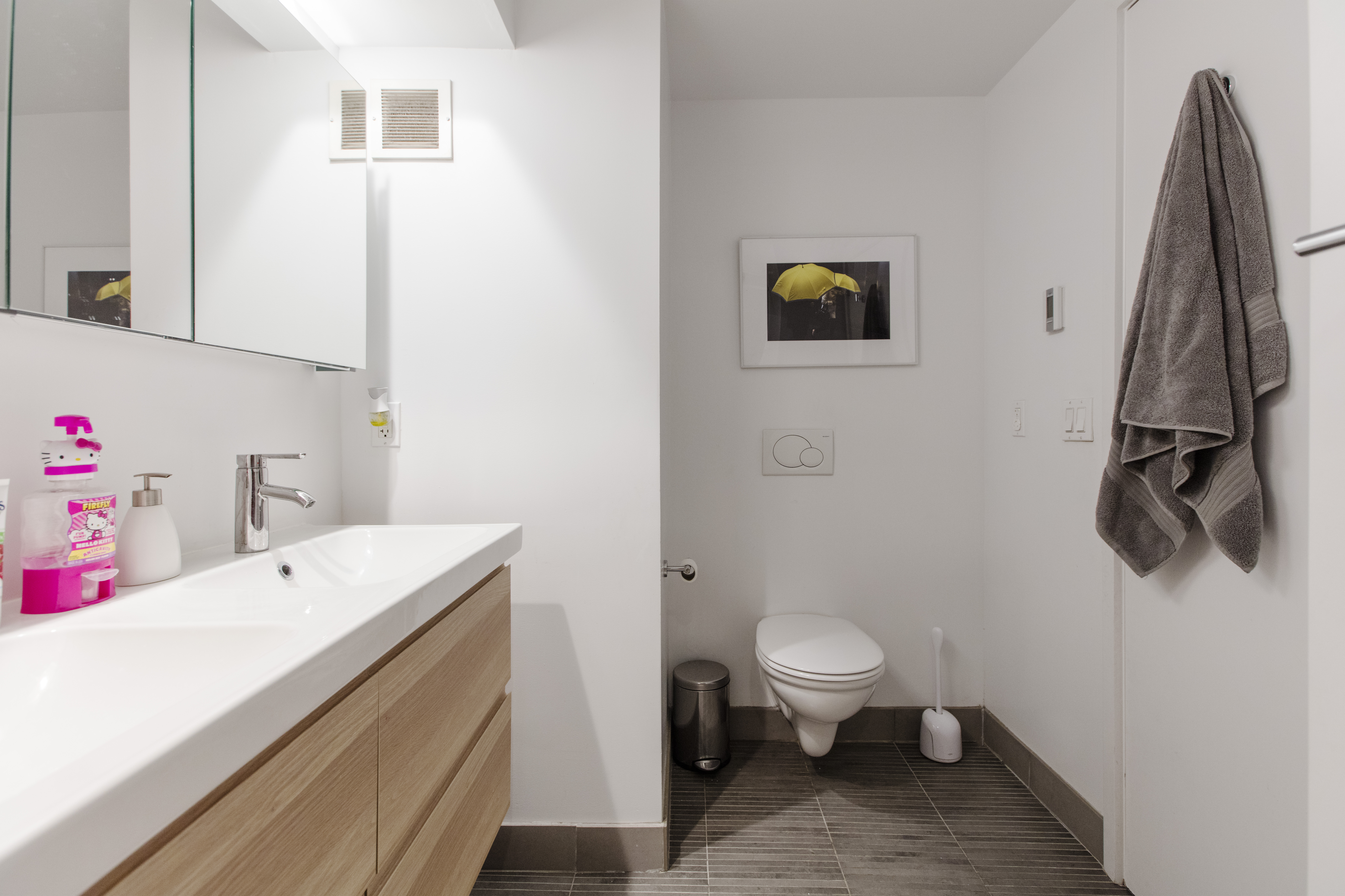 Remodeled bathroom with white walls, floating toilet, and vanity mirrors