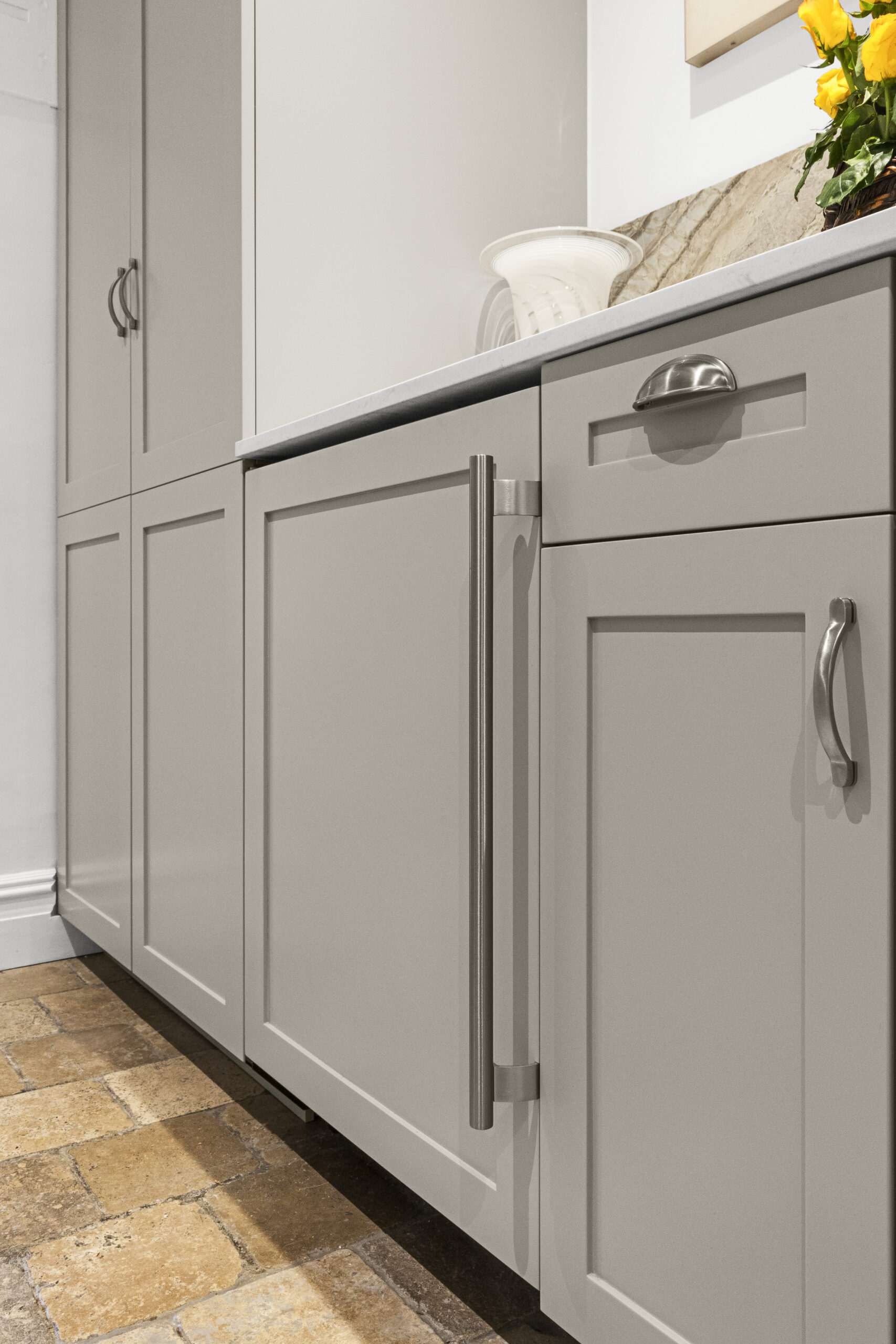 A renovated kitchen with gray Shaker cabinets, satin nickel cabinet hardware, and porcelain tile flooring