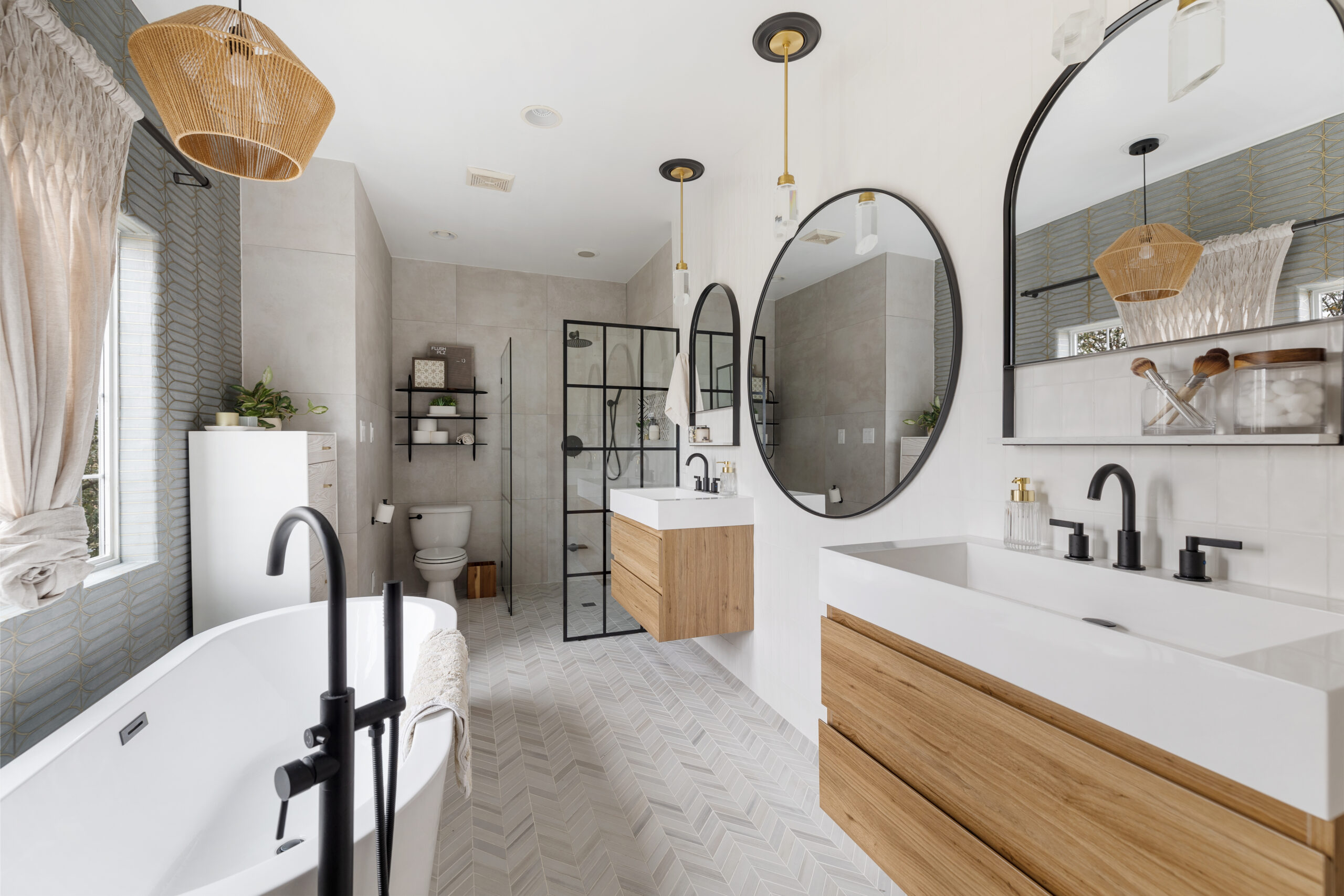 Remodeled bathroom with arched mirrors, floating vanity, and herringbone floor tiles