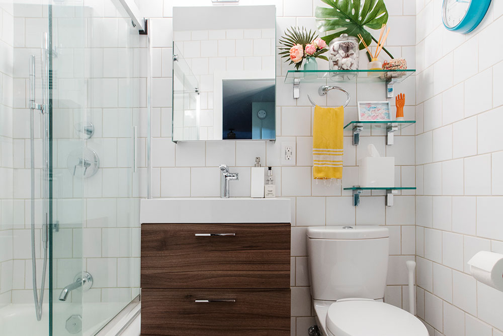 Bathroom remodel with clean-lined mirror, dark wood vanity, white tile walls, and open glass shelves