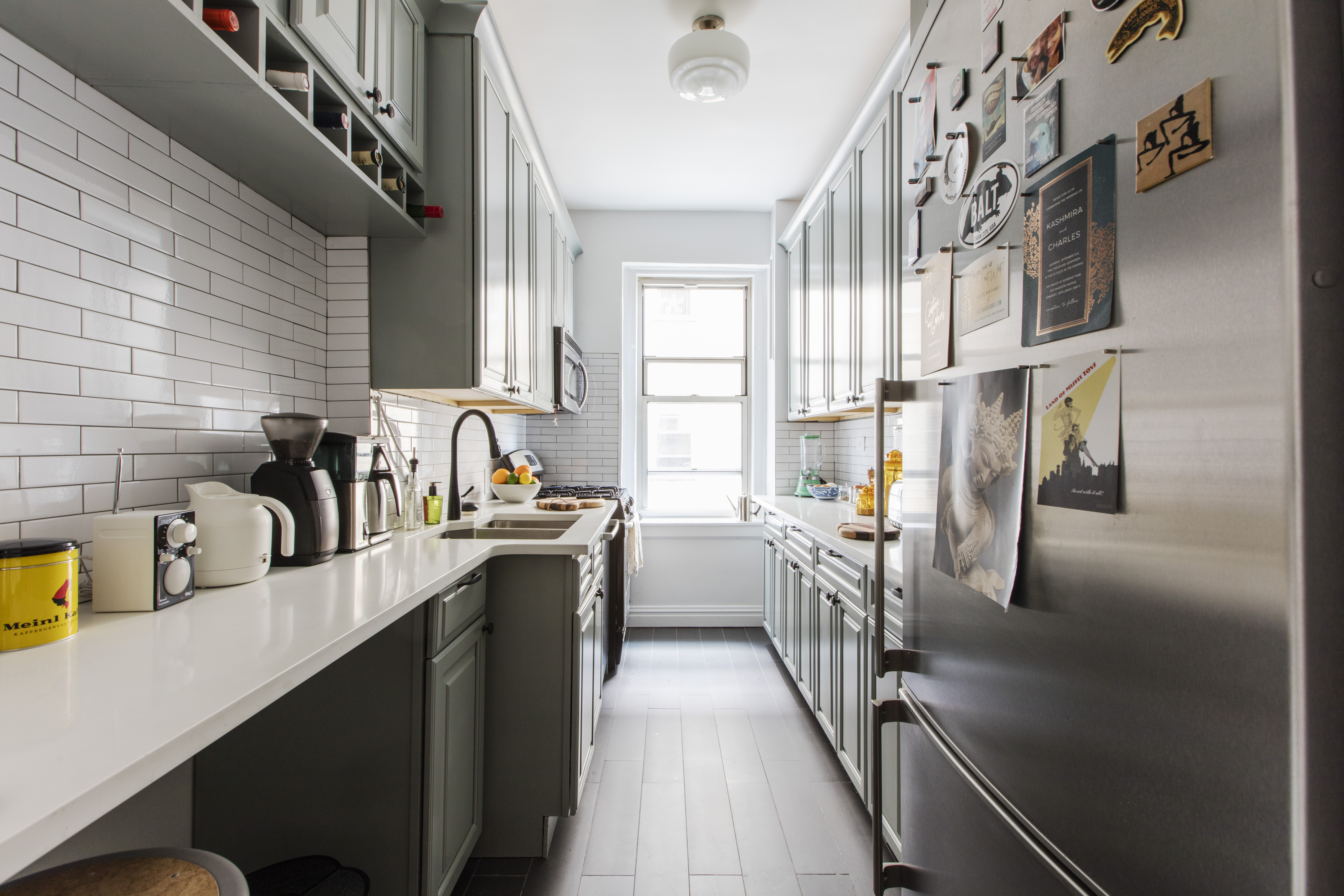 Upper Manhattan kitchen that used white subway tile backsplash, black floor tile, white quartz counter, and stainless steel appliances