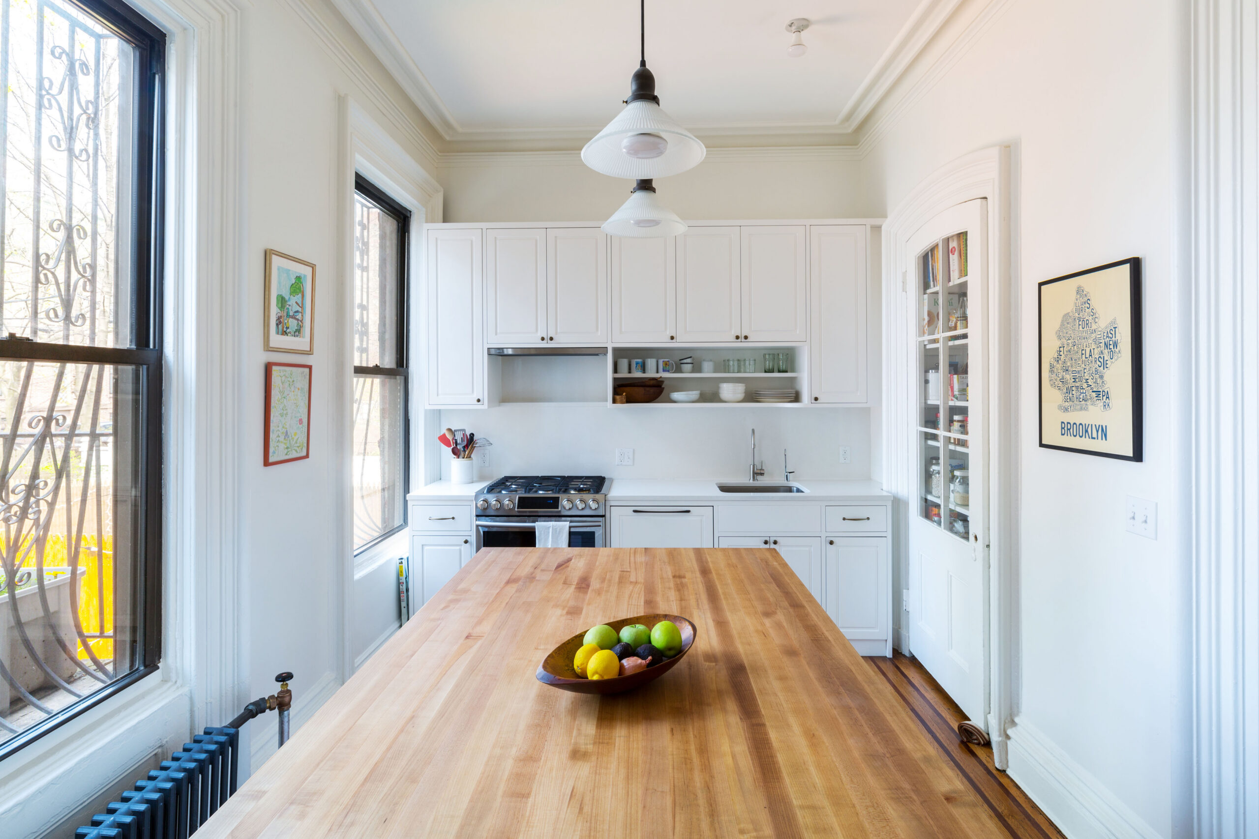 A remodeled kitchen in Brooklyn with butcher block island, white cabinetry, and wood flooring