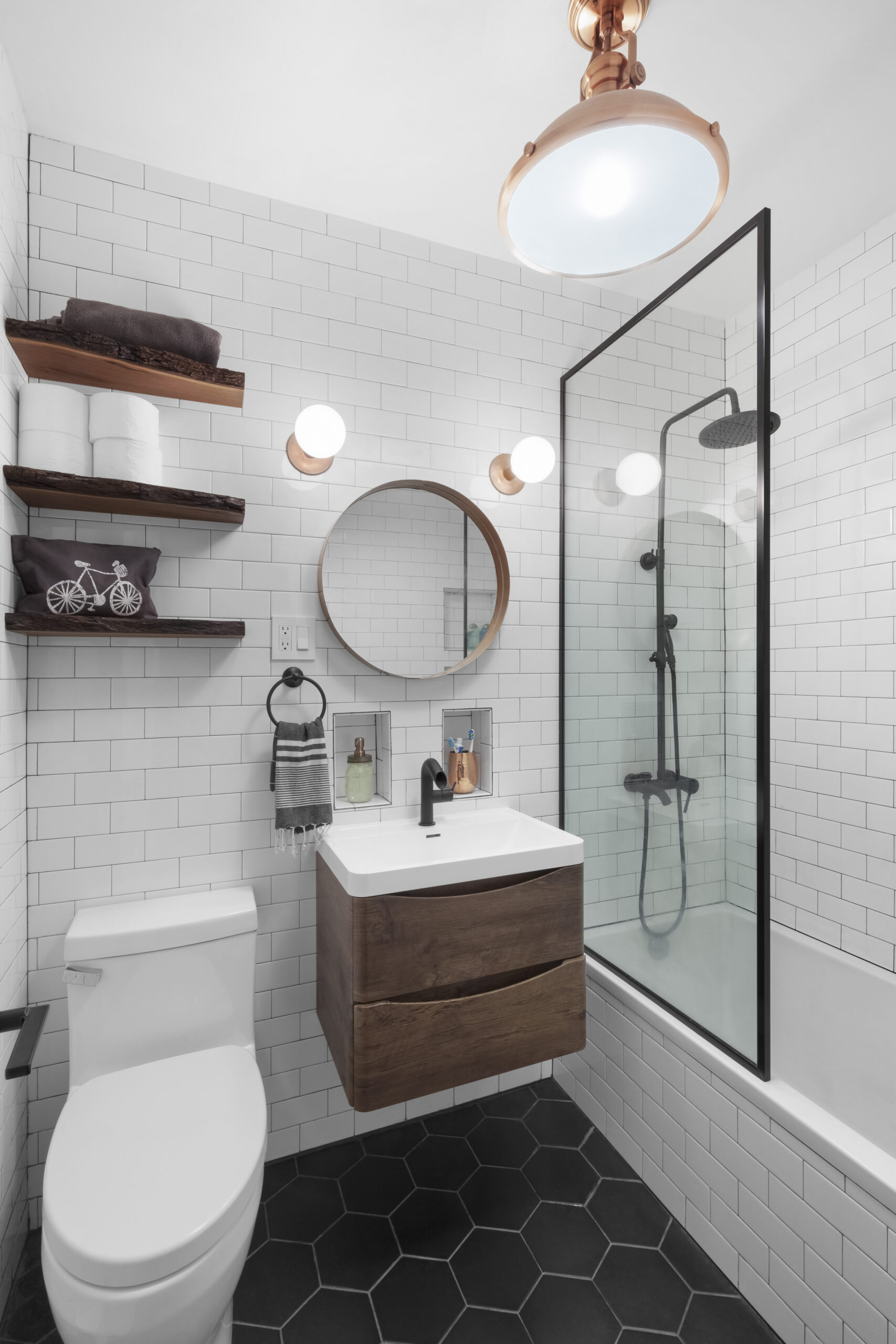 A renovated bathroom in Park Slope featuring white subway wall tile, black hex flooring, and floating vanity