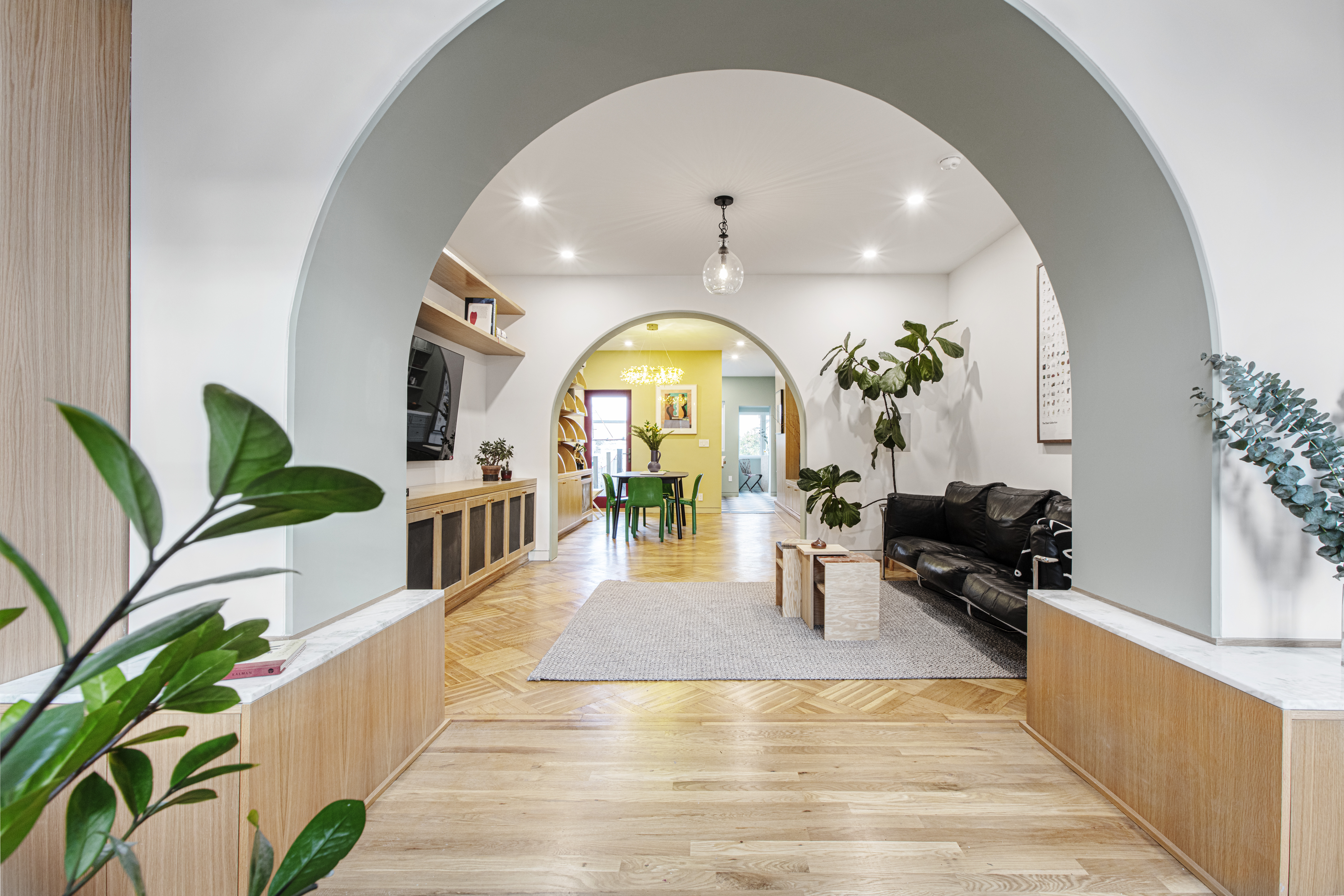 Glendale historic home renovation in a rowhouse with arched openings, pale wood floors, built-in storage, and open living-to-dining flow.