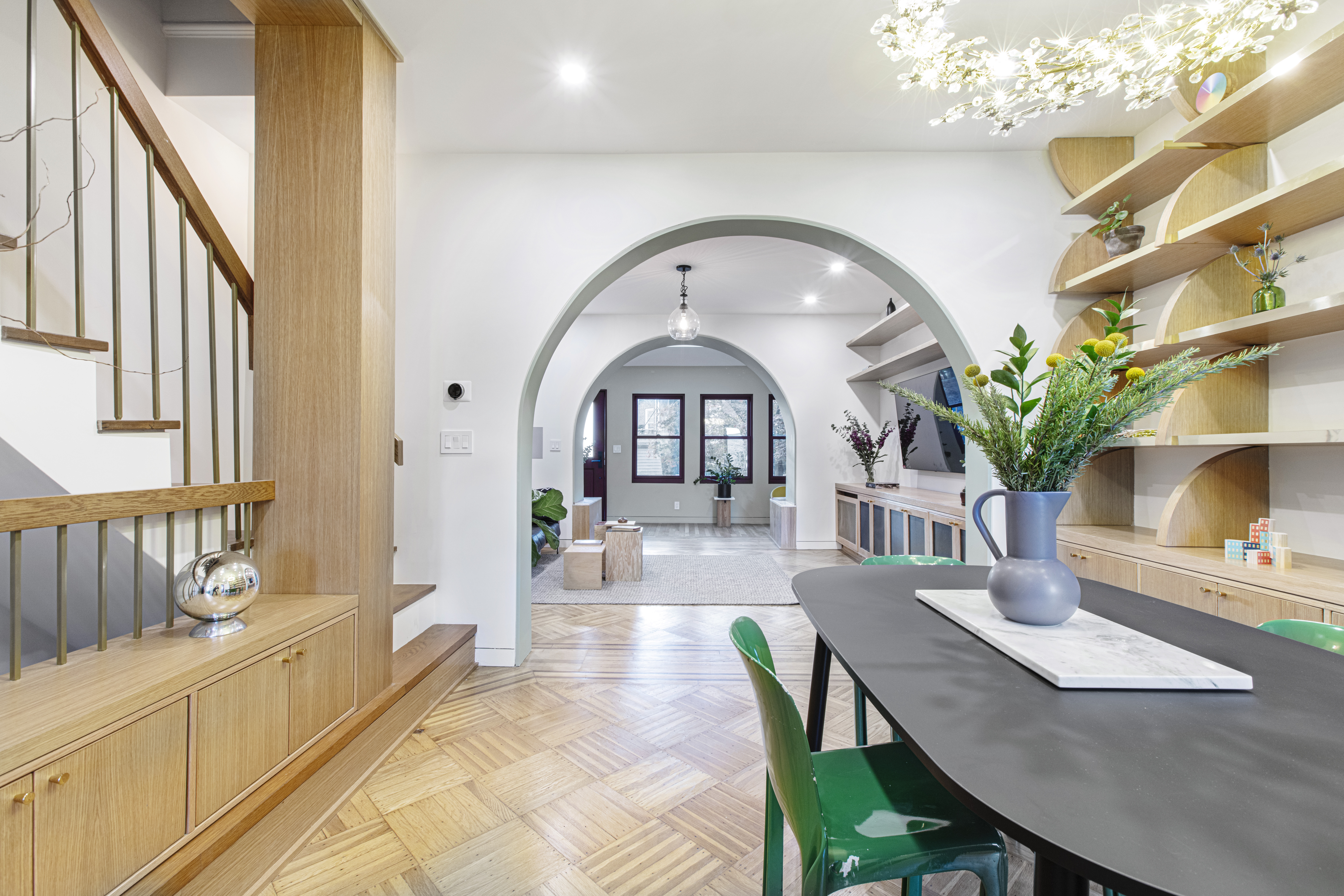 Glendale dining area after historic home renovation with arched opening, wood floors, custom shelving, stair storage, and curved millwork.