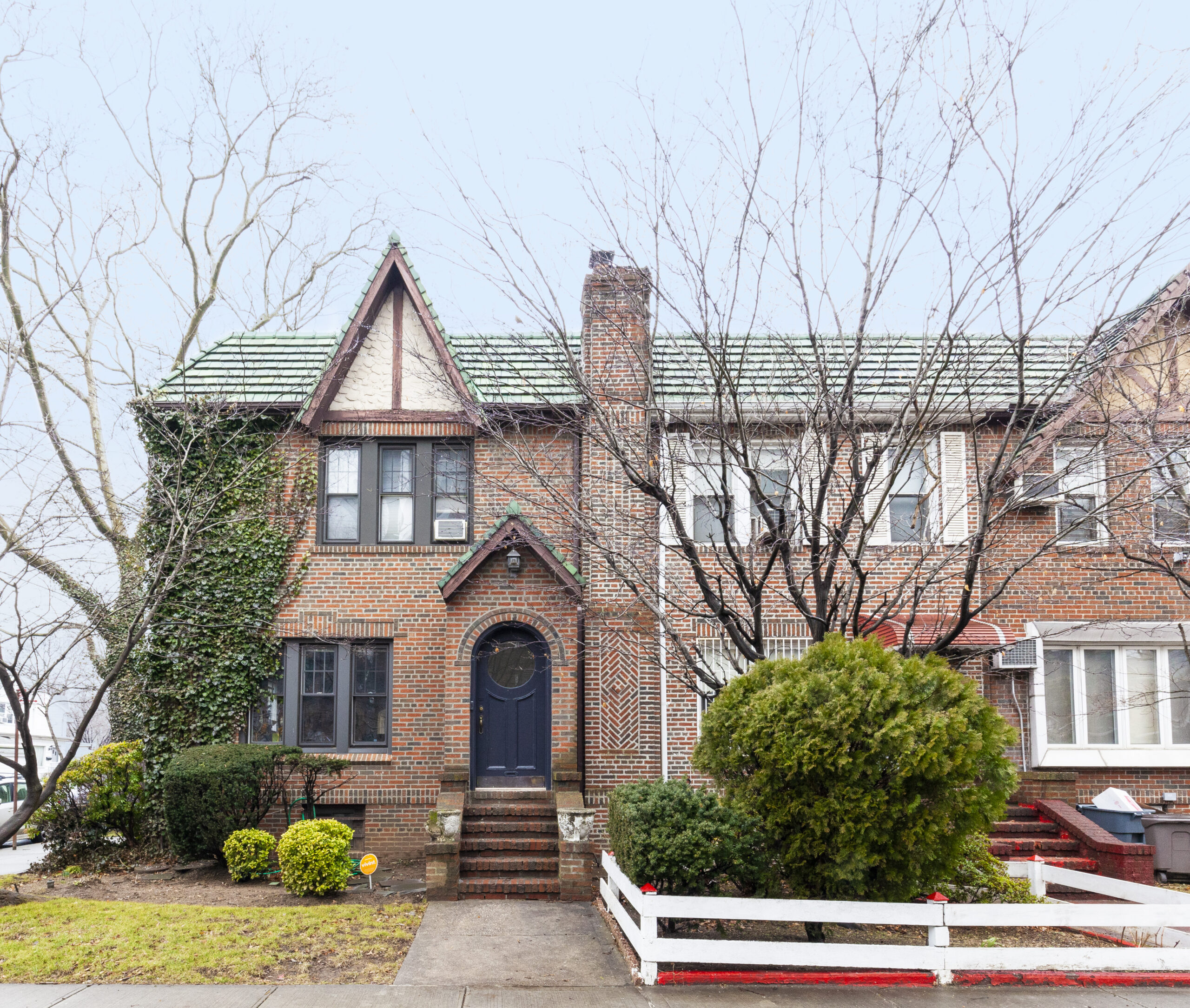 South Slope historic home renovation exterior with red brick, steep gables, green roof tiles, arched entry, and 1920s Tudor character.