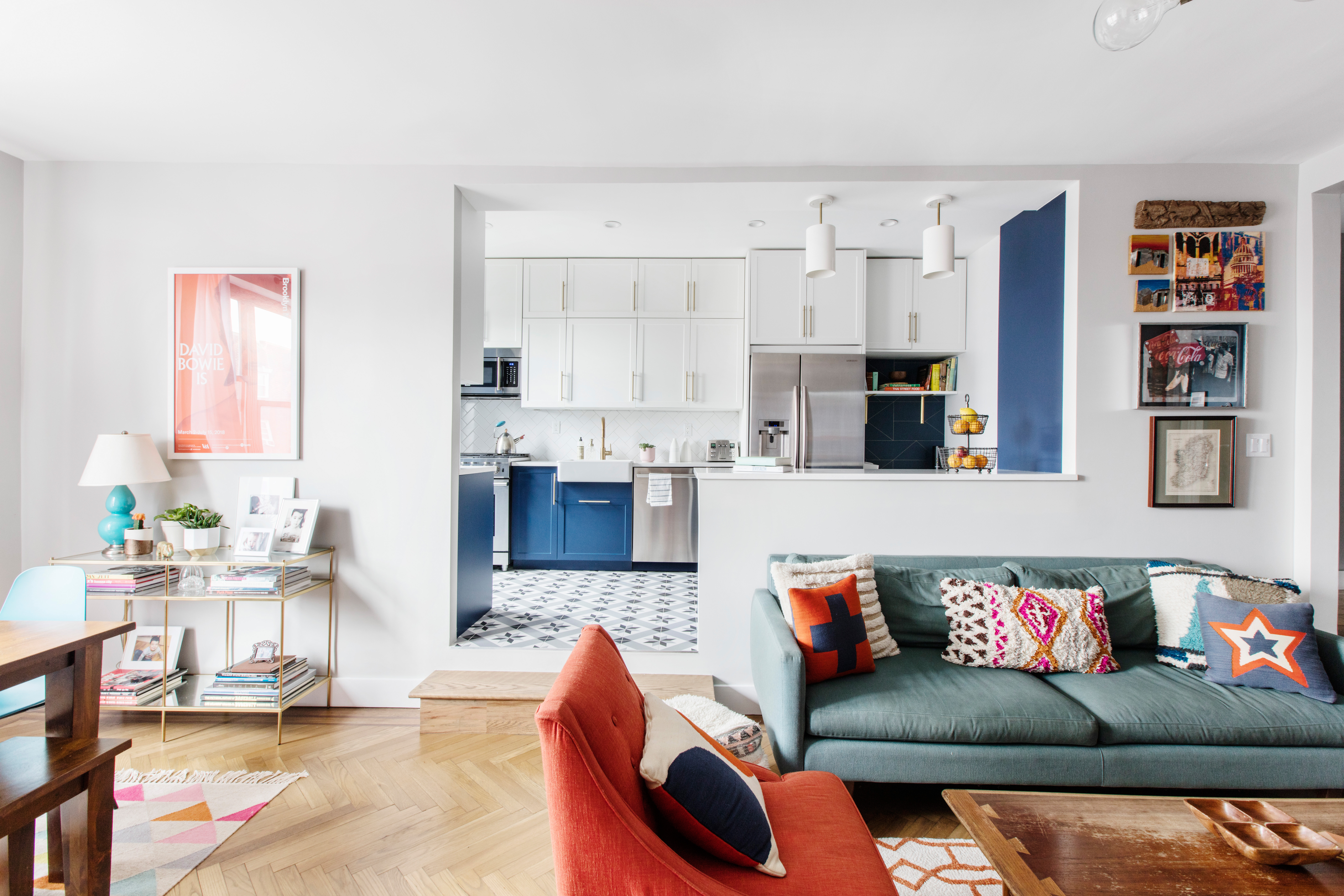 A Kensington whole home renovation opens a kitchen with blue cabinetry and patterned tile to a living area with white walls and warm wood floors.