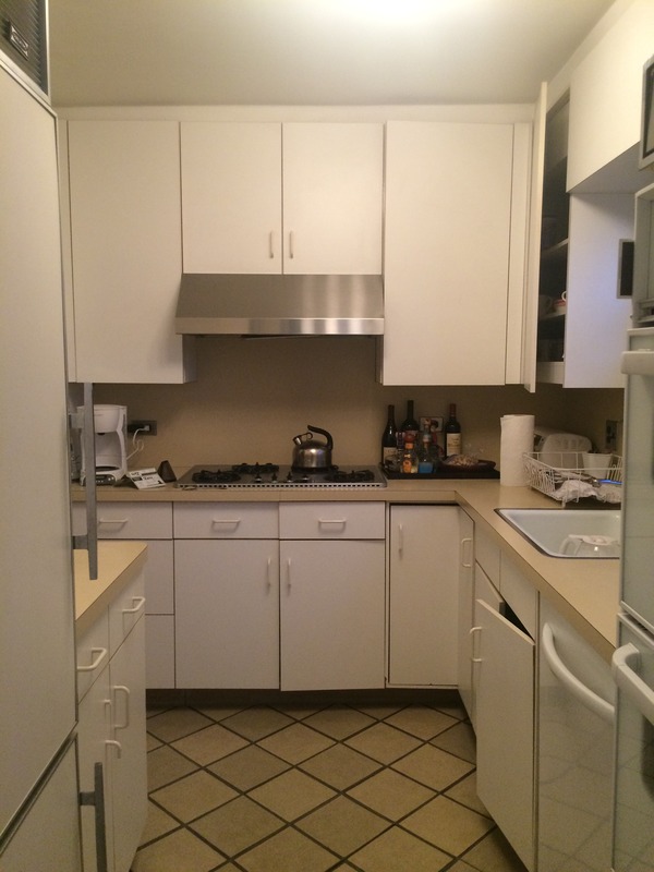 New York City kitchen before renovation, showing older white cabinets, tile flooring, compact counters, and the layout later refreshed in the remodel.