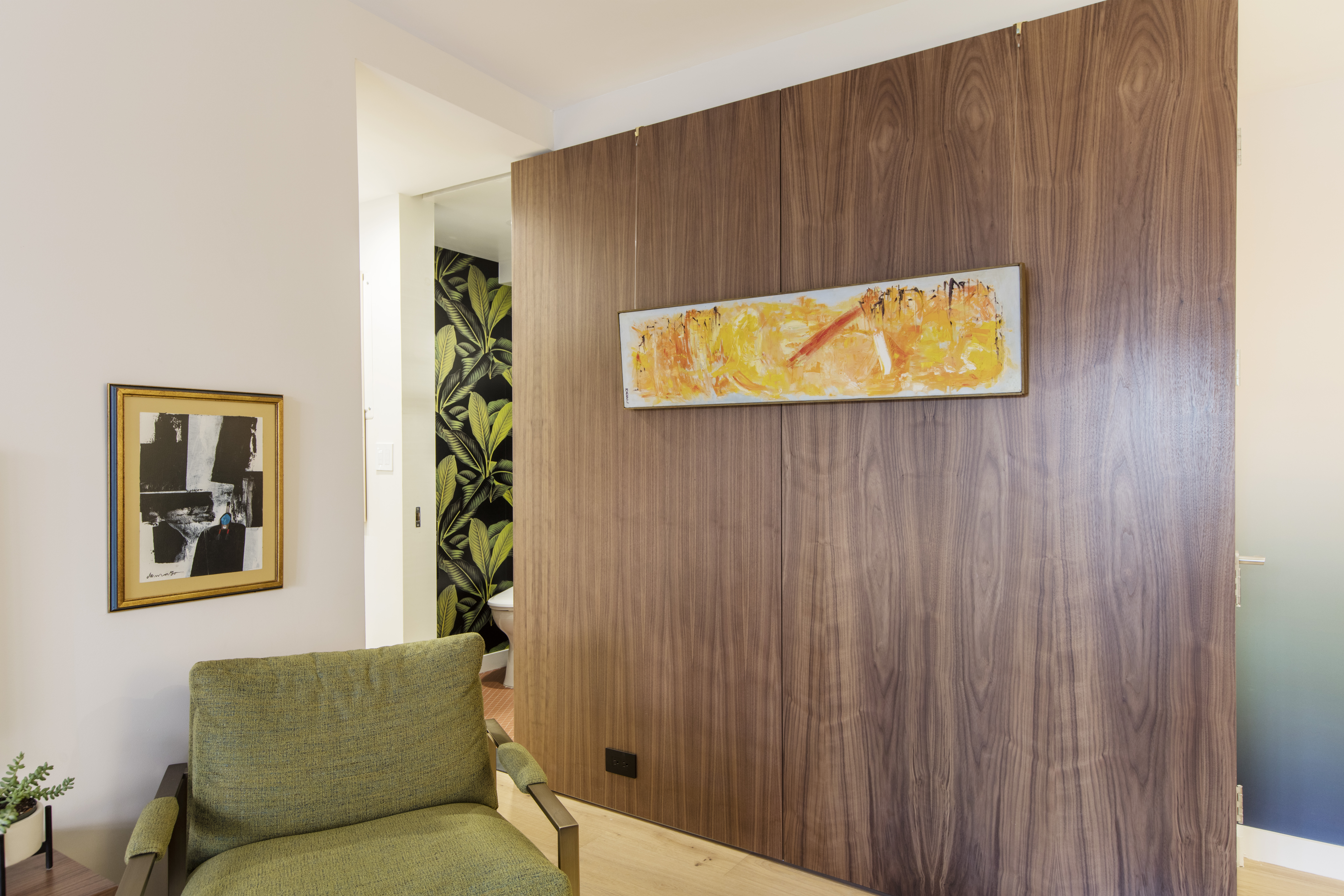Walnut wall panel in this Clinton Hill living room extends the divider’s warm wood palette and creates a strong visual break within the open layout.