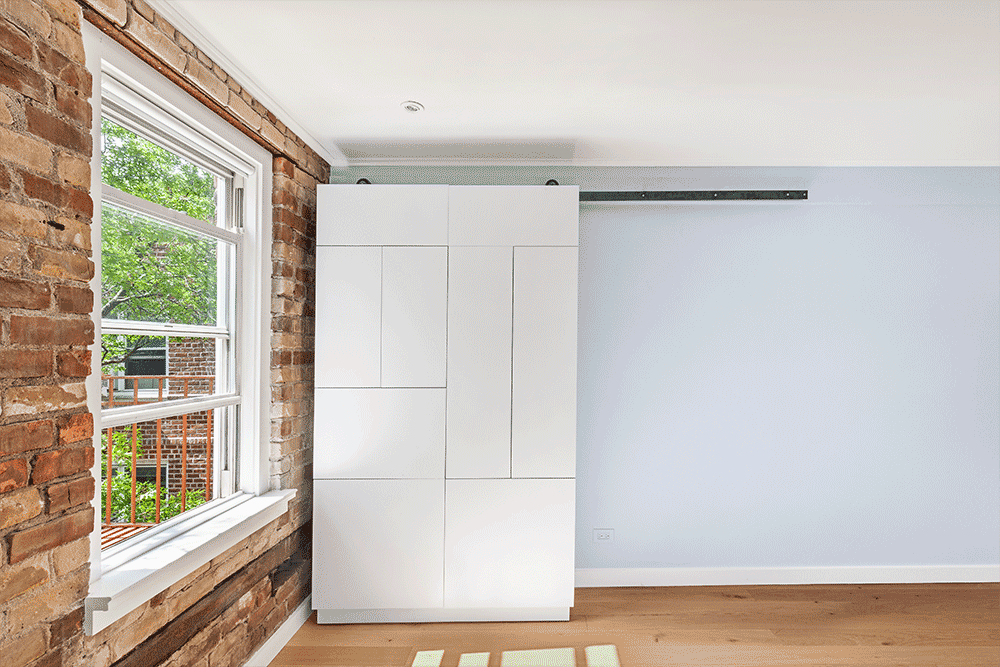 Sliding wardrobe room divider in Cobble Hill moves along a wall-mounted rail, adding bedroom privacy and closet storage without blocking the window.