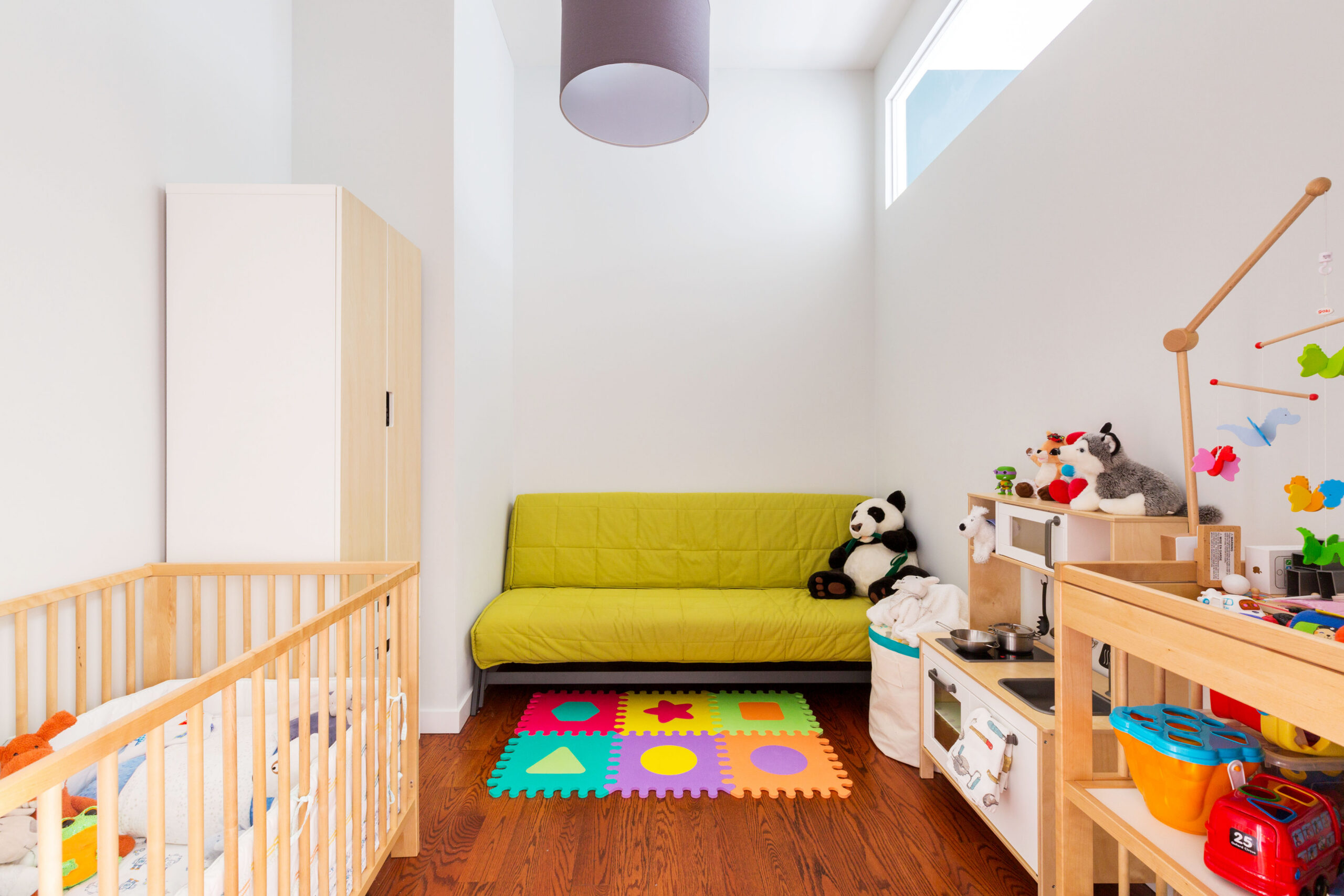 A high transom window in Downtown Brooklyn brings borrowed daylight into a nursery created with full-height walls and space-saving pocket doors.