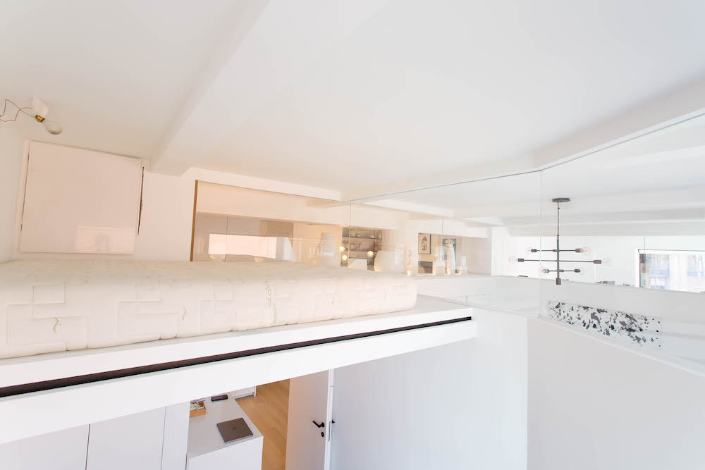 Greenwich Village extra bedroom idea with lofted bed, clerestory glass, white walls, high ceiling, open sightlines, and shared natural light.