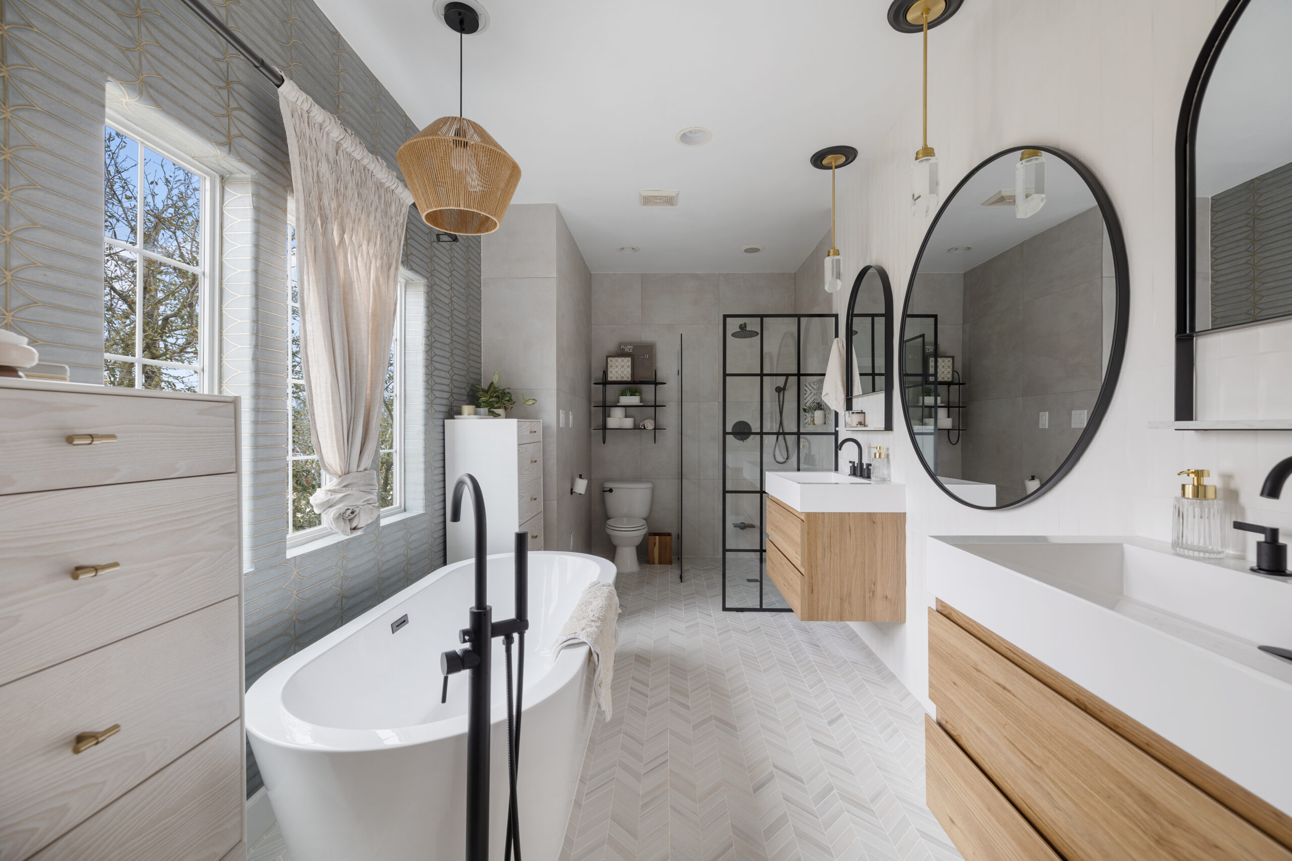 Houston bathroom with matte black tub and shower hardware, brass vanity pulls and lights, floating wood vanities, and a black-framed enclosure.