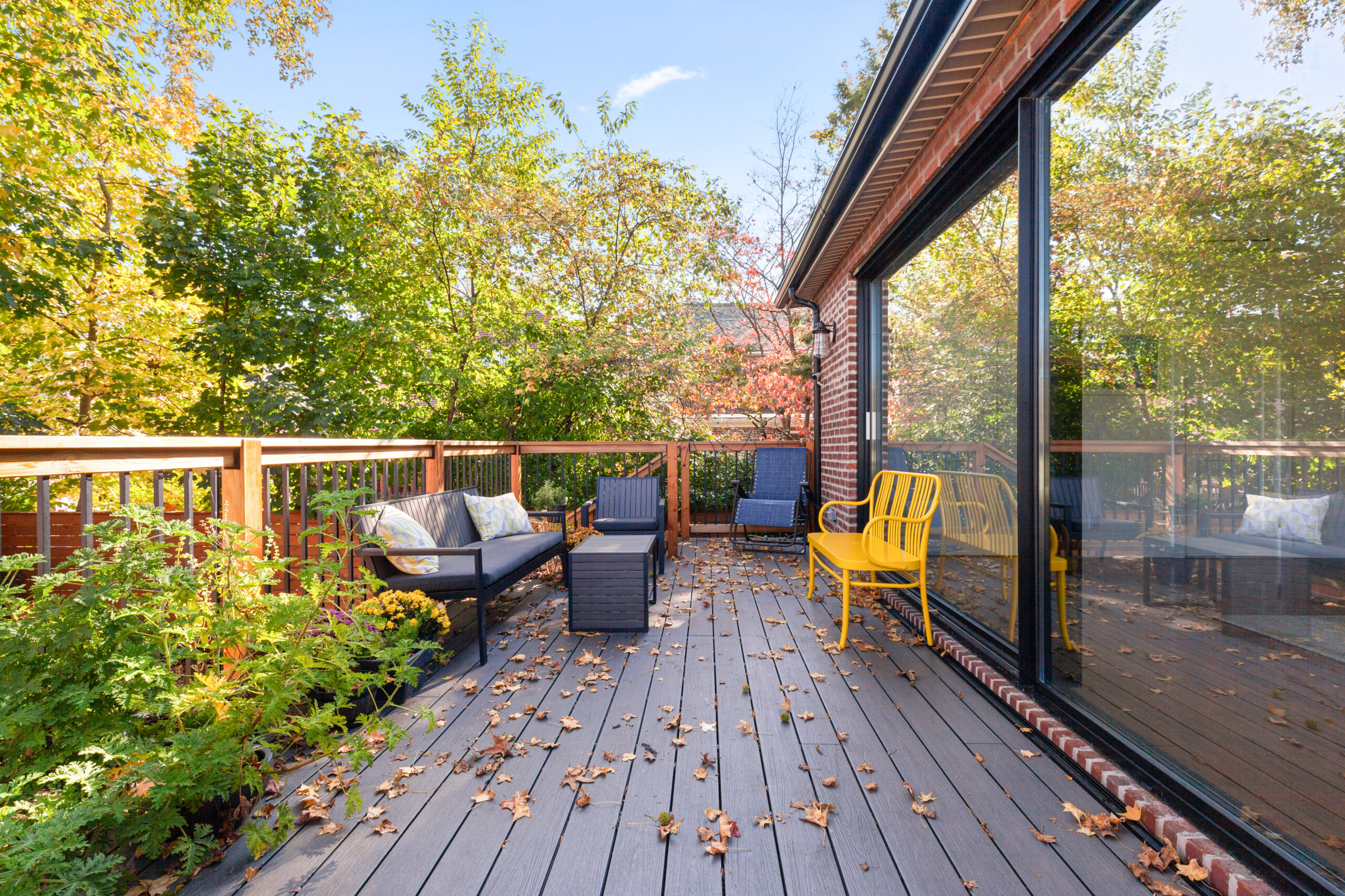 Morris Park raised deck with composite panels, wood and metal railings, planted borders, seating area and wide black framed glass wall.