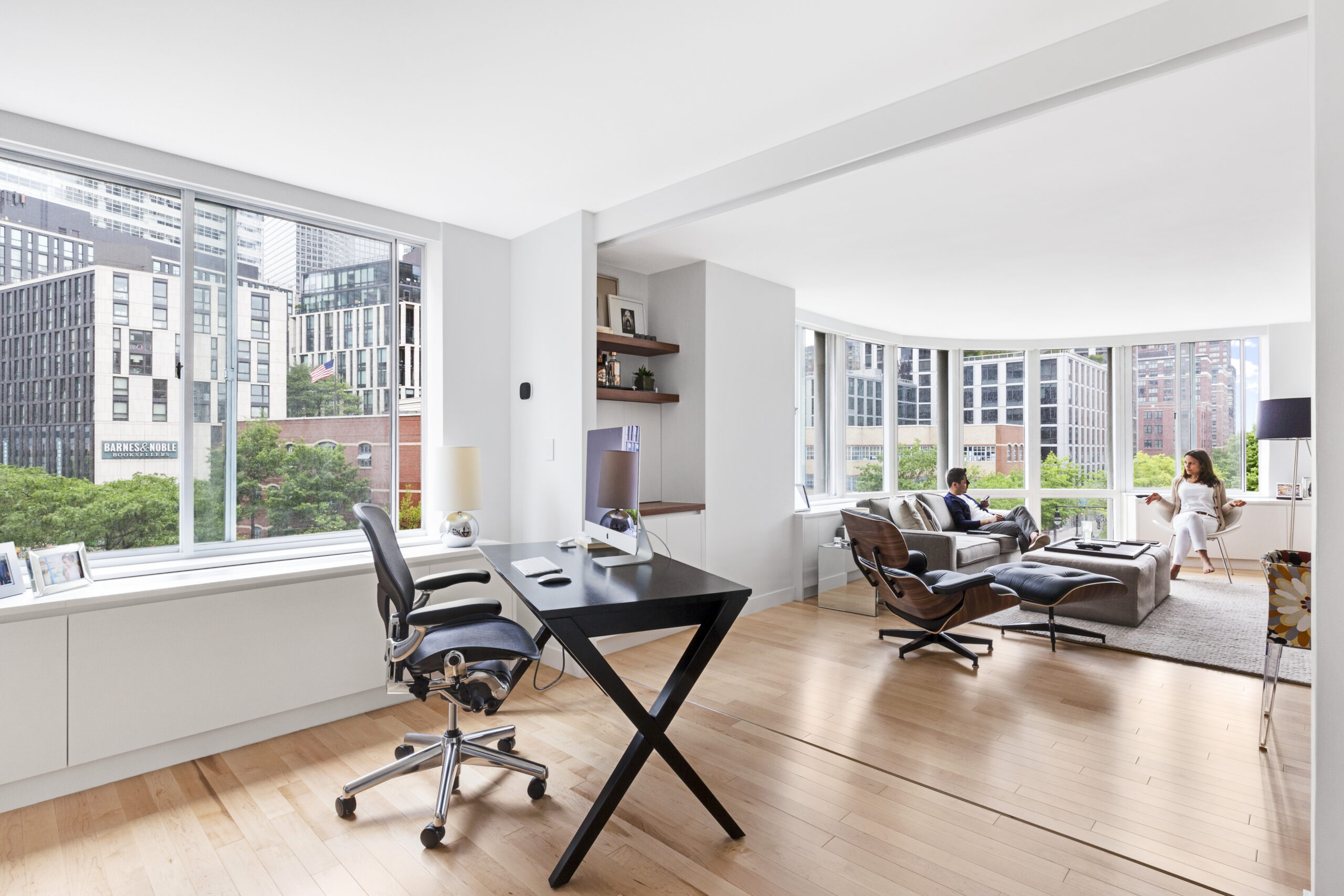 Open sliding panels connect this Tribeca office to the living room, preserving daylight and wide sightlines while keeping the guest suite flexible.