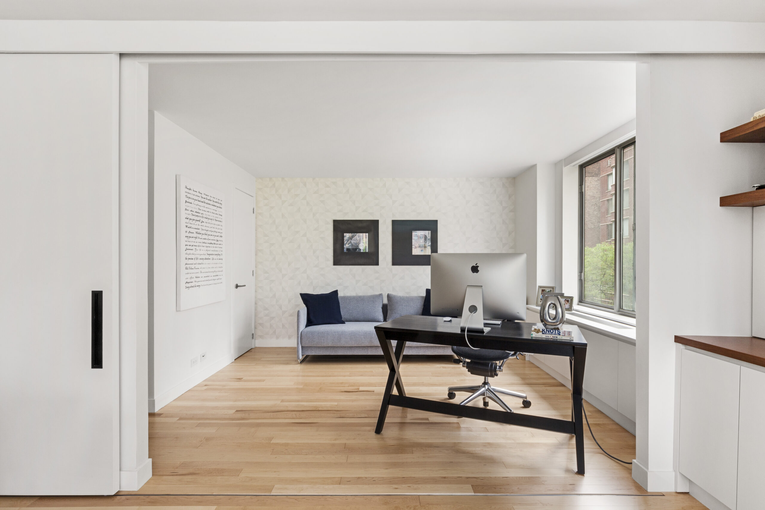 Oversized white sliding panels frame a Tribeca home office, creating a flexible room divider that can close the workspace into a private guest suite.
