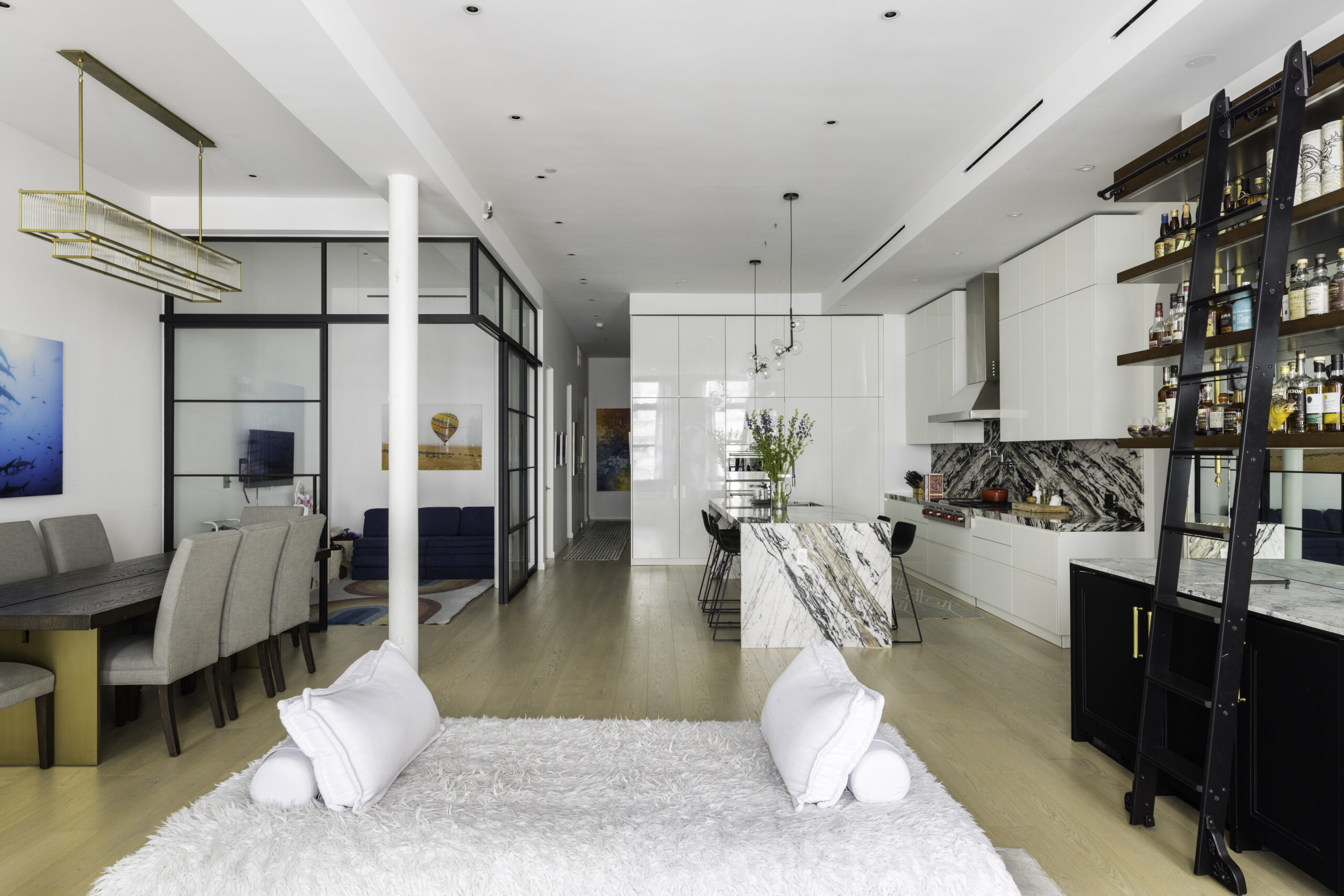 Wide view of a Union Square loft shows the glass playroom divider beside the dining area and kitchen, keeping the open layout bright and connected.