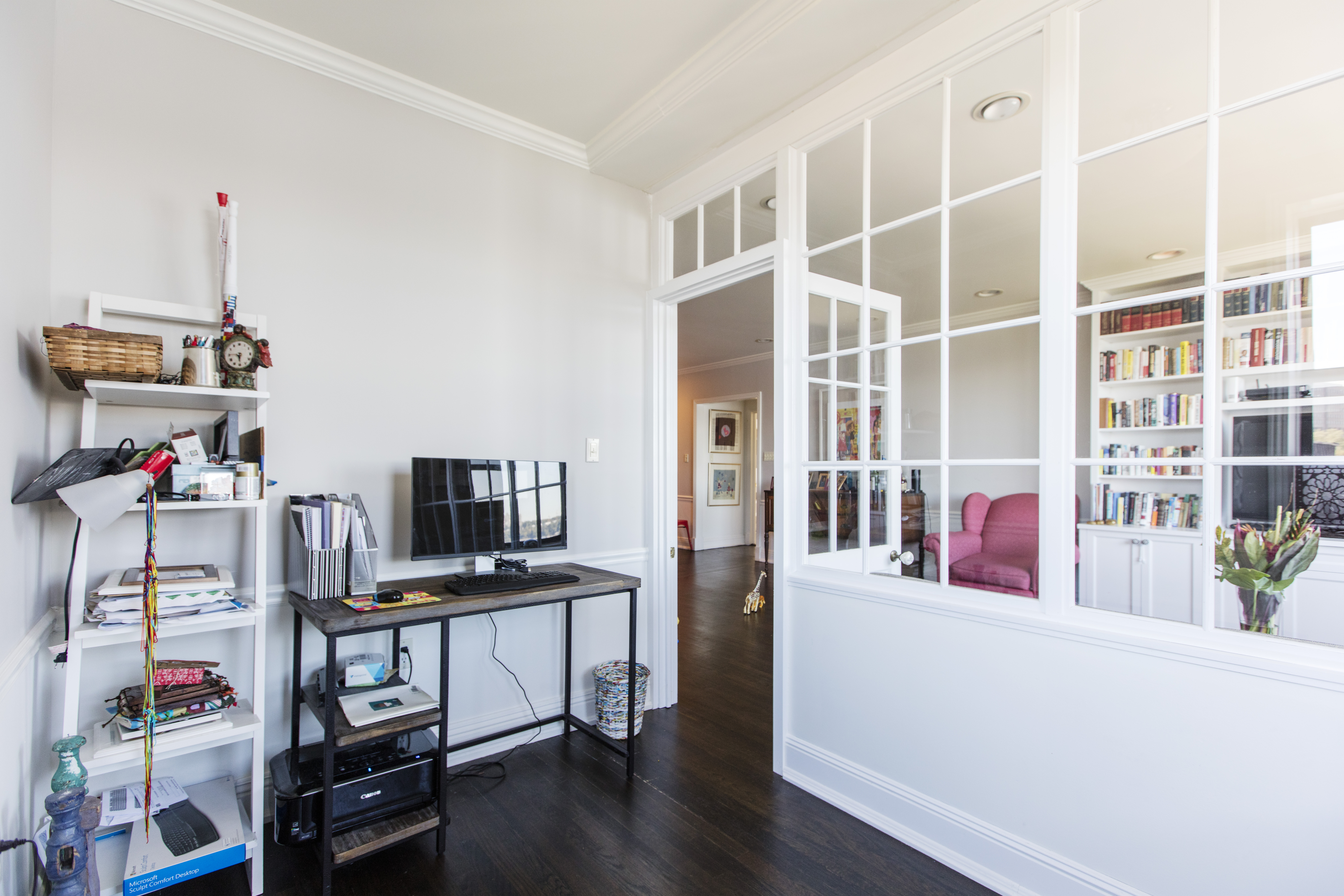 White-framed interior windows in Washington Heights divide a guest room and office from the living area while keeping both spaces bright and connected.