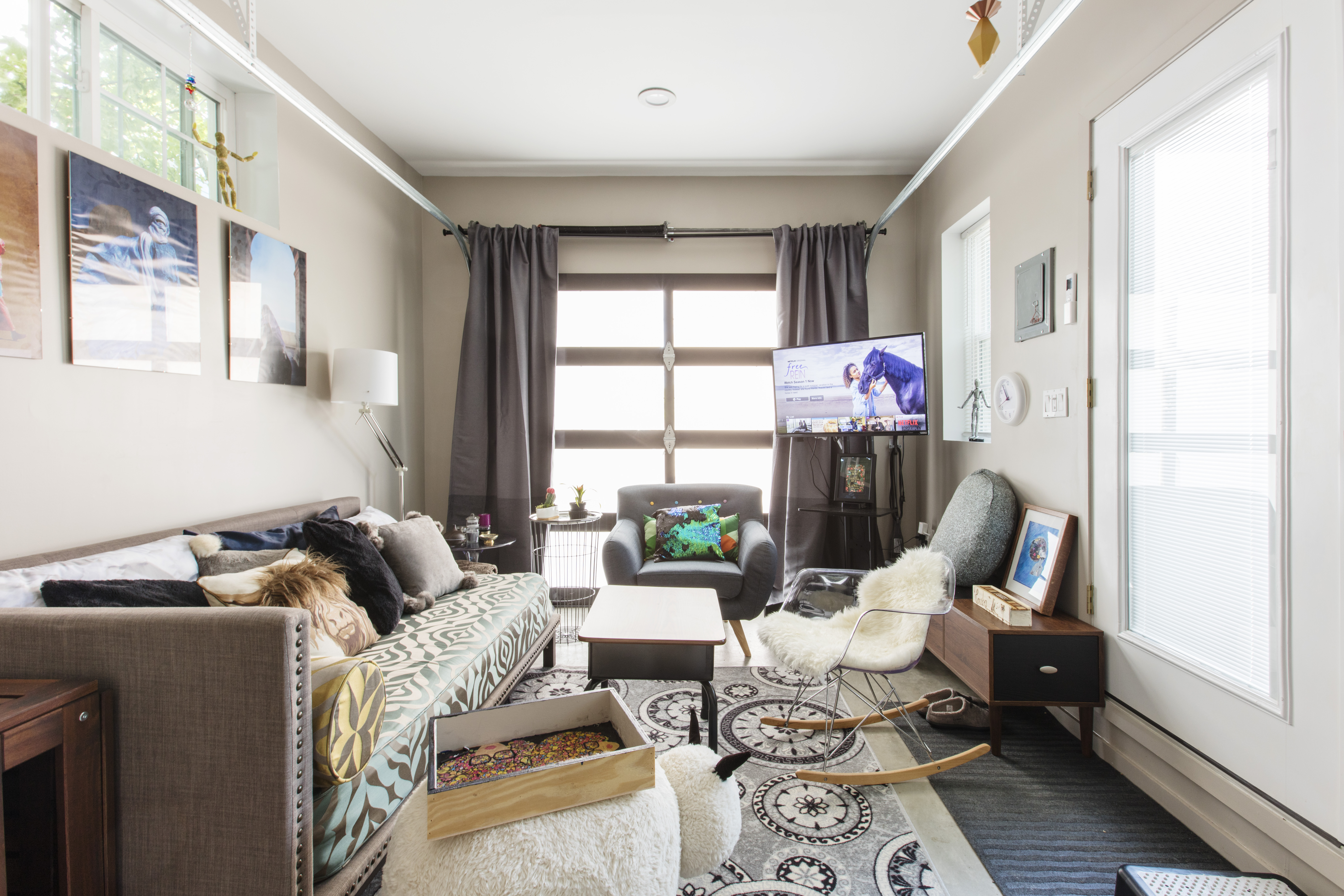 Queens custom ADU living room with a daybed, lounge seating, patterned rugs, and a frosted garage door that brings in soft daylight.