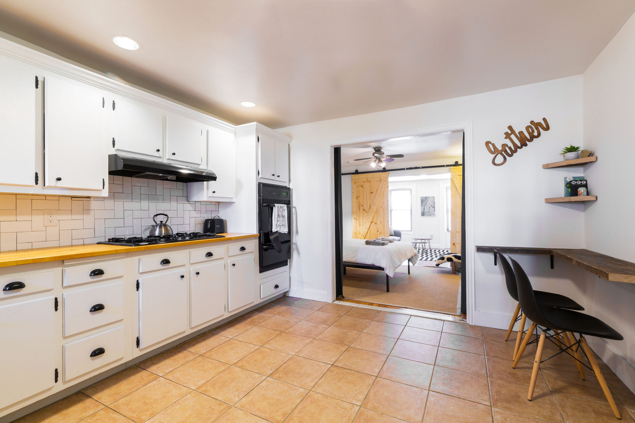Bed-Stuy townhouse design with white cabinets, wood counters, subway tile, tiled floors, a wide opening, and a compact breakfast ledge for the rental unit.