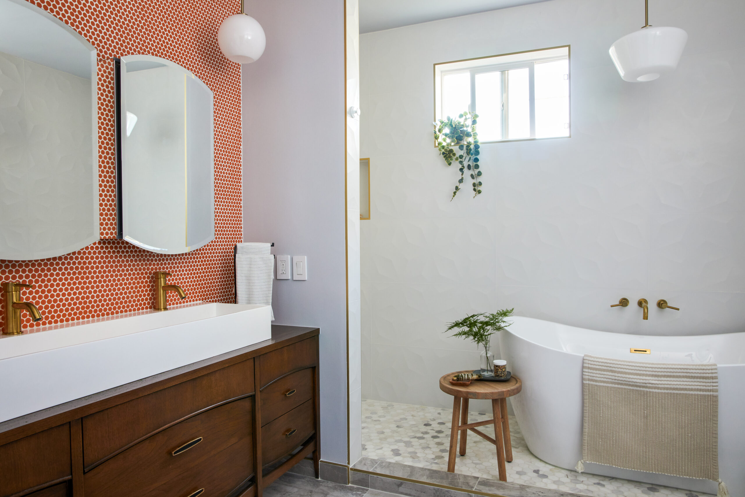 Los Angeles primary bathroom features a converted walnut dresser vanity, white trough sink, red penny tile, brass fixtures, and freestanding tub.