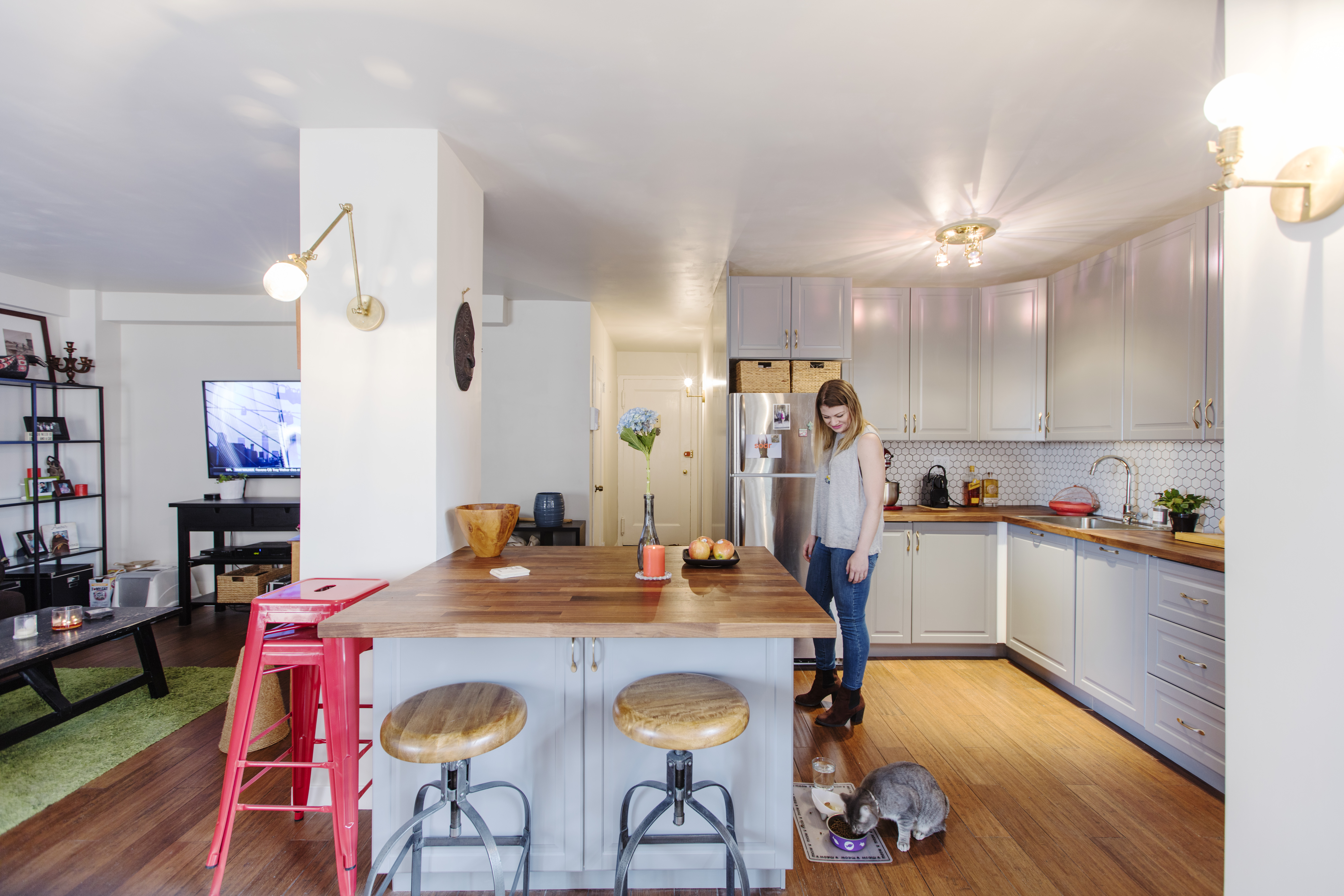 Rego Park townhouse design with gray cabinetry, wood counters, hex tile backsplash, hardwood floors, and a large island opening toward the living room.