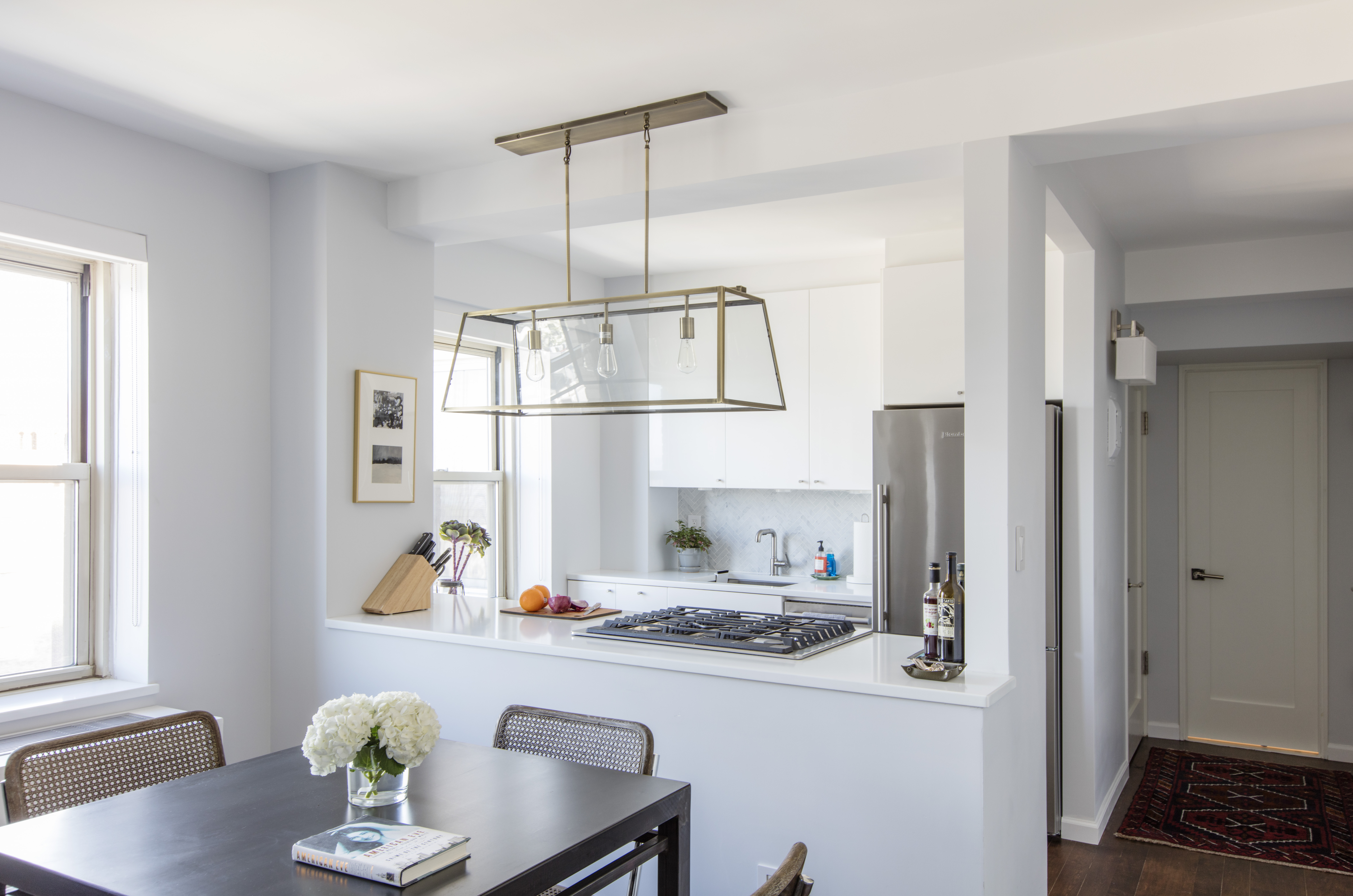 Brooklyn Heights small apartment kitchen with white cabinets, a quartz counter, stainless steel appliances, and a glass pendant above the dining table.